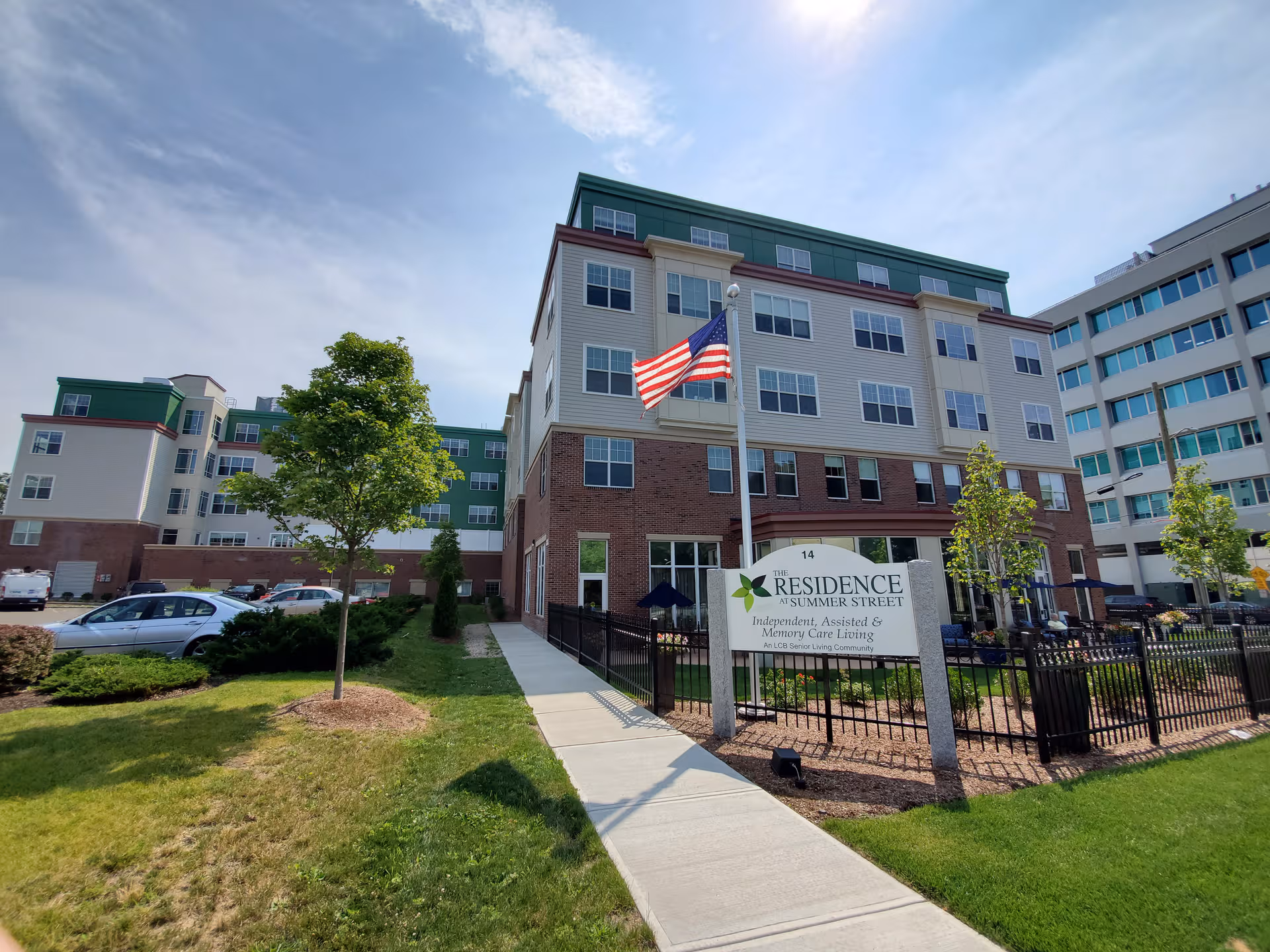 Exterior view of The Residence at Summer Street, a senior living facility, with flag and sign.