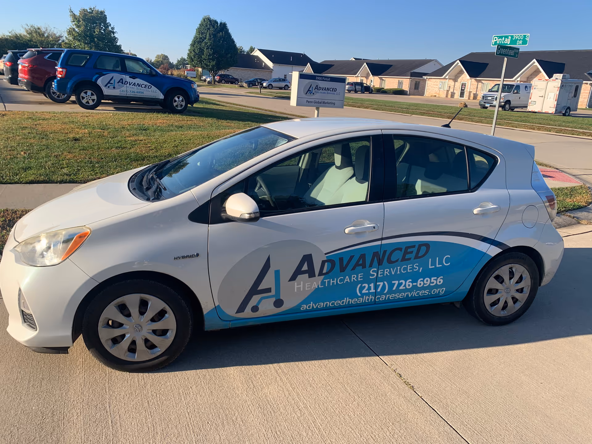 White sedan with Advanced Healthcare Services LLC branding parked in a suburban parking lot