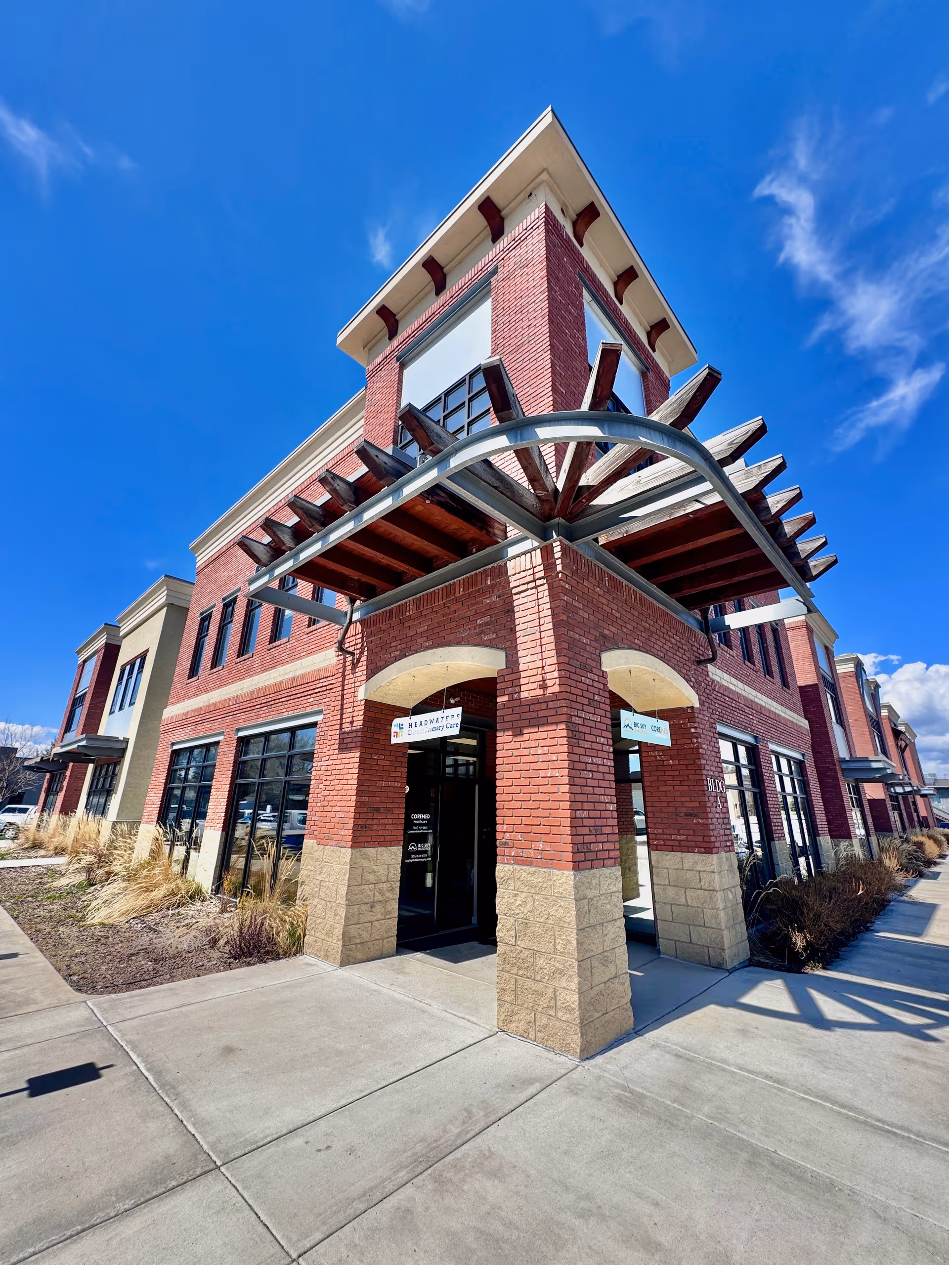 Brick senior living facility building with metal canopy entrance and blue sky.