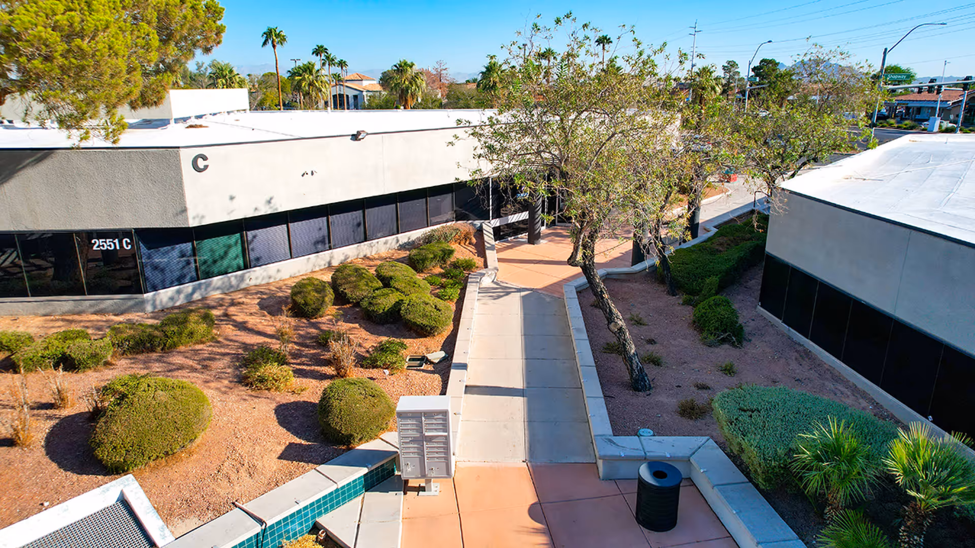 Aerial view of a courtyard between two beige buildings with trees and walkways.