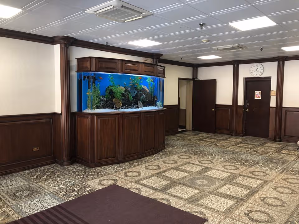 Wide lobby area with a large aquarium in dark wood cabinetry along paneled walls