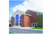 Exterior view of a brick senior living facility with a tall arched window.