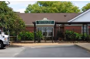 Exterior view of St. Francis Home entrance with sign and surrounding greenery.