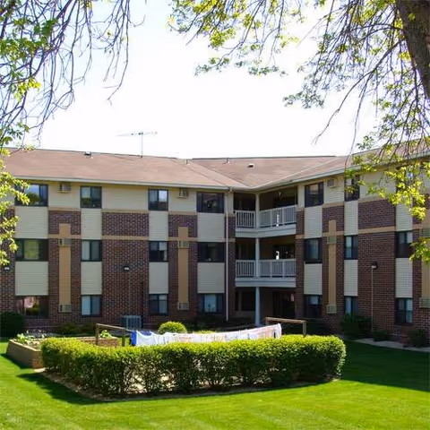 Exterior view of Oak Ridge Manor showing a brick apartment building with balconies and landscaped lawn.