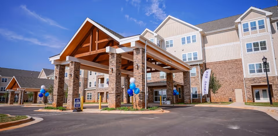 A senior living facility entrance with a stone-pillared porte-cochere and beige multi-story building.
