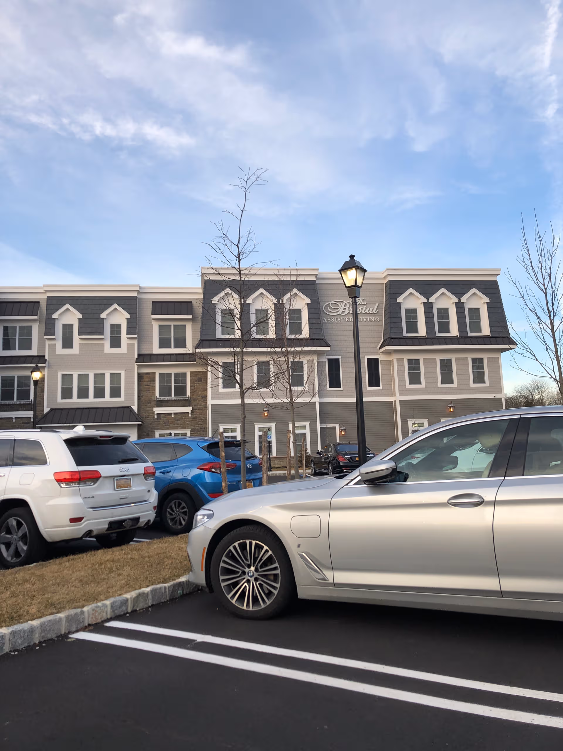 Exterior view of The Bristal Assisted Living at Jericho with parked cars.