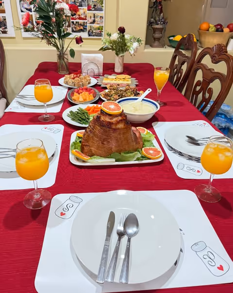 Dining table set for a feast with roasted turkey centerpiece and orange drinks.