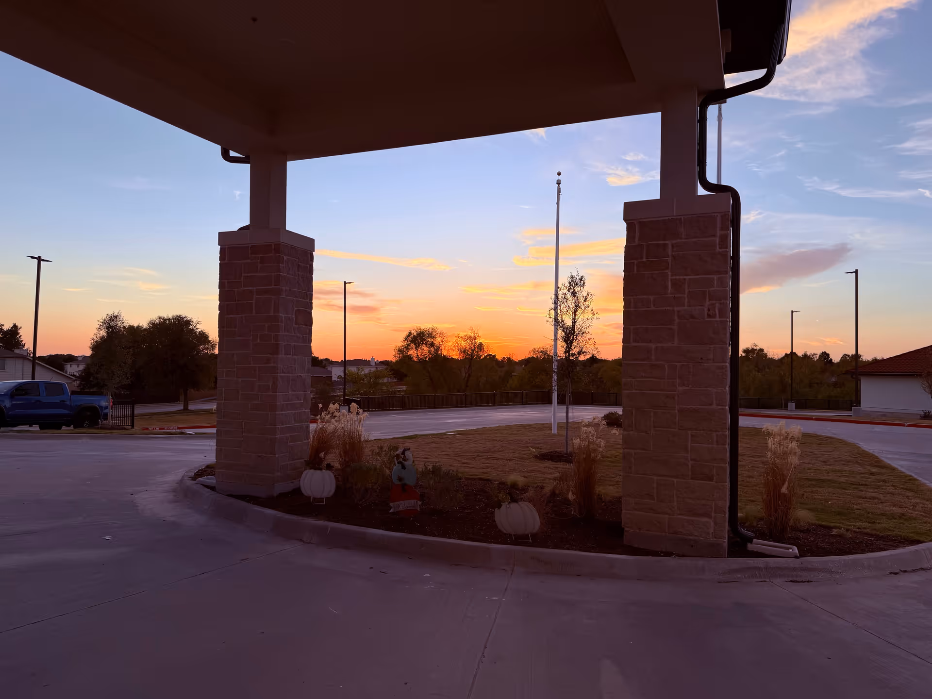 Sunset view of The Emberly at Heritage Glen entrance with stone pillars.