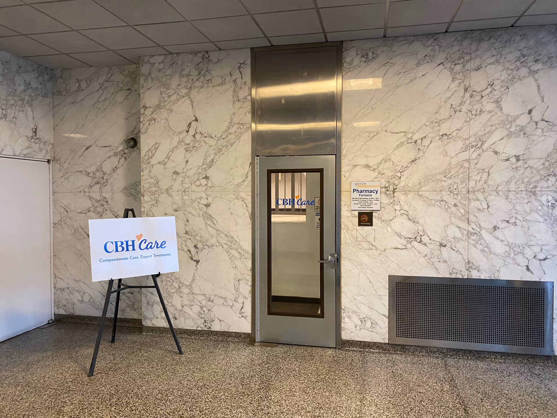 Marble-walled interior hallway with a CBH Care door and a freestanding sign.