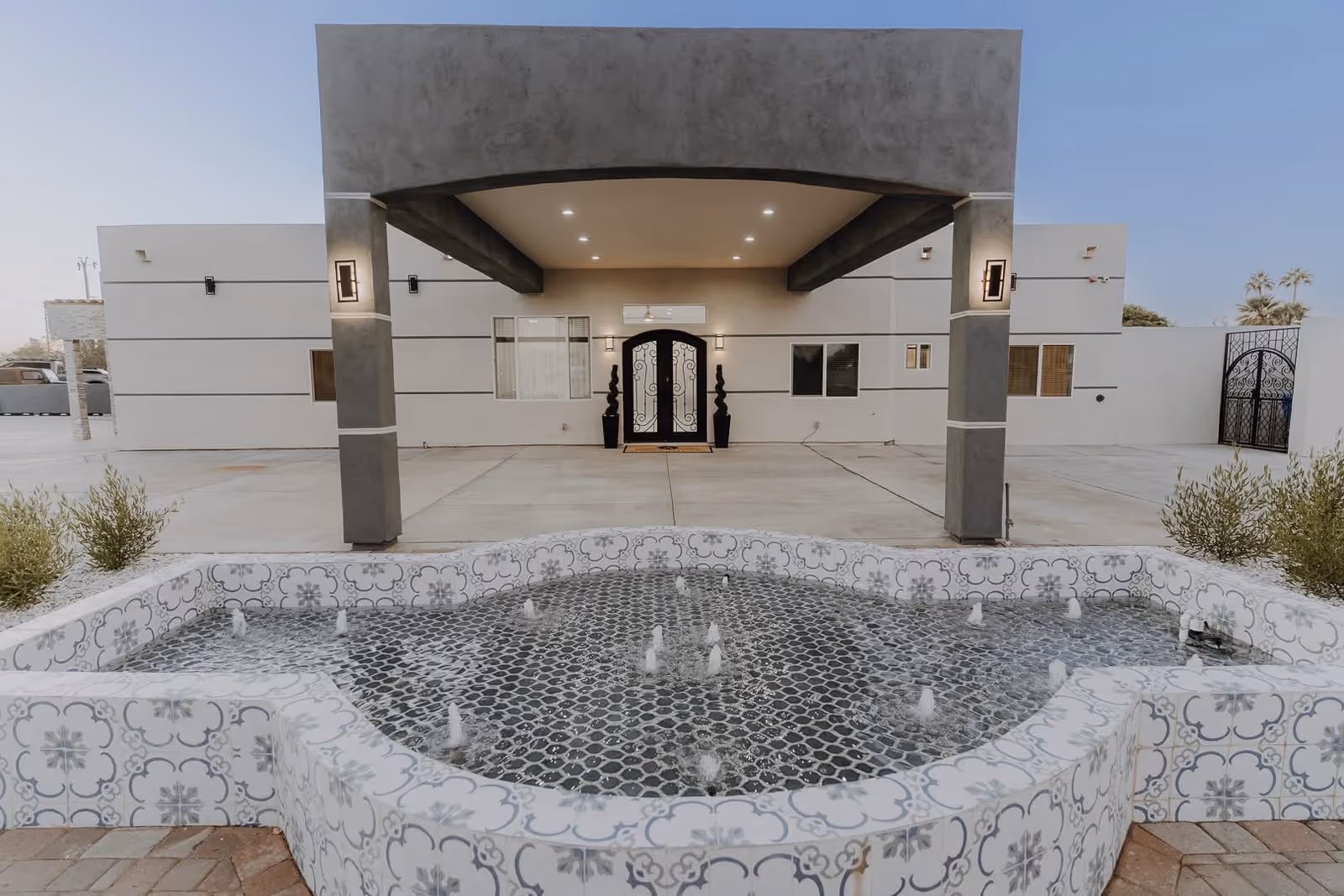 Front view of a modern senior living facility exterior with a decorative fountain.