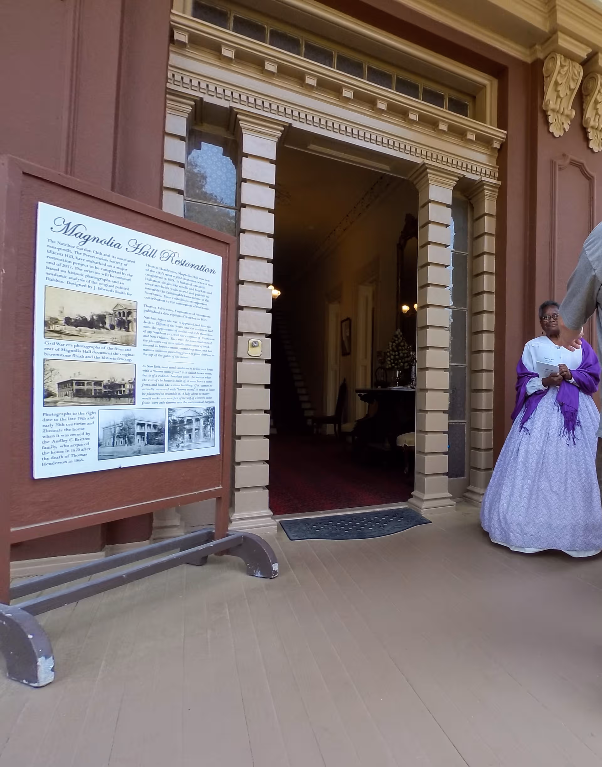 Magnolia Hall entrance with an informational board and a person in period dress.