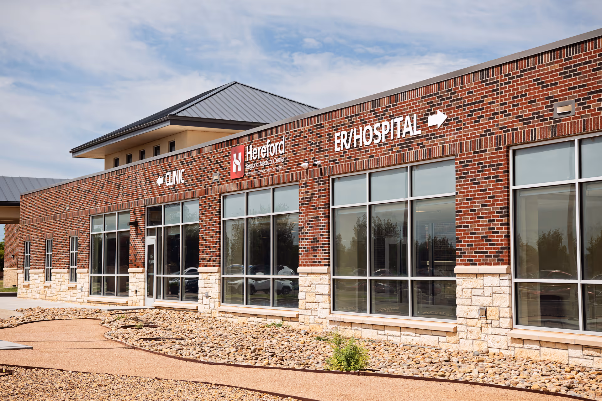 Brick medical clinic exterior with large windows and ER/Hospital signage