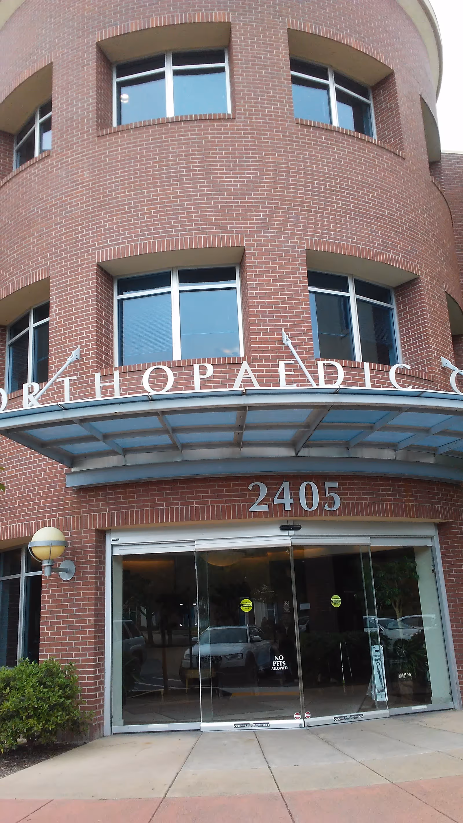 Brick curved facade of a senior facility with glass entry doors and address 2405.