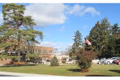 Front view of Hanover Hall senior living facility with trees, lawn, flag, and cars.