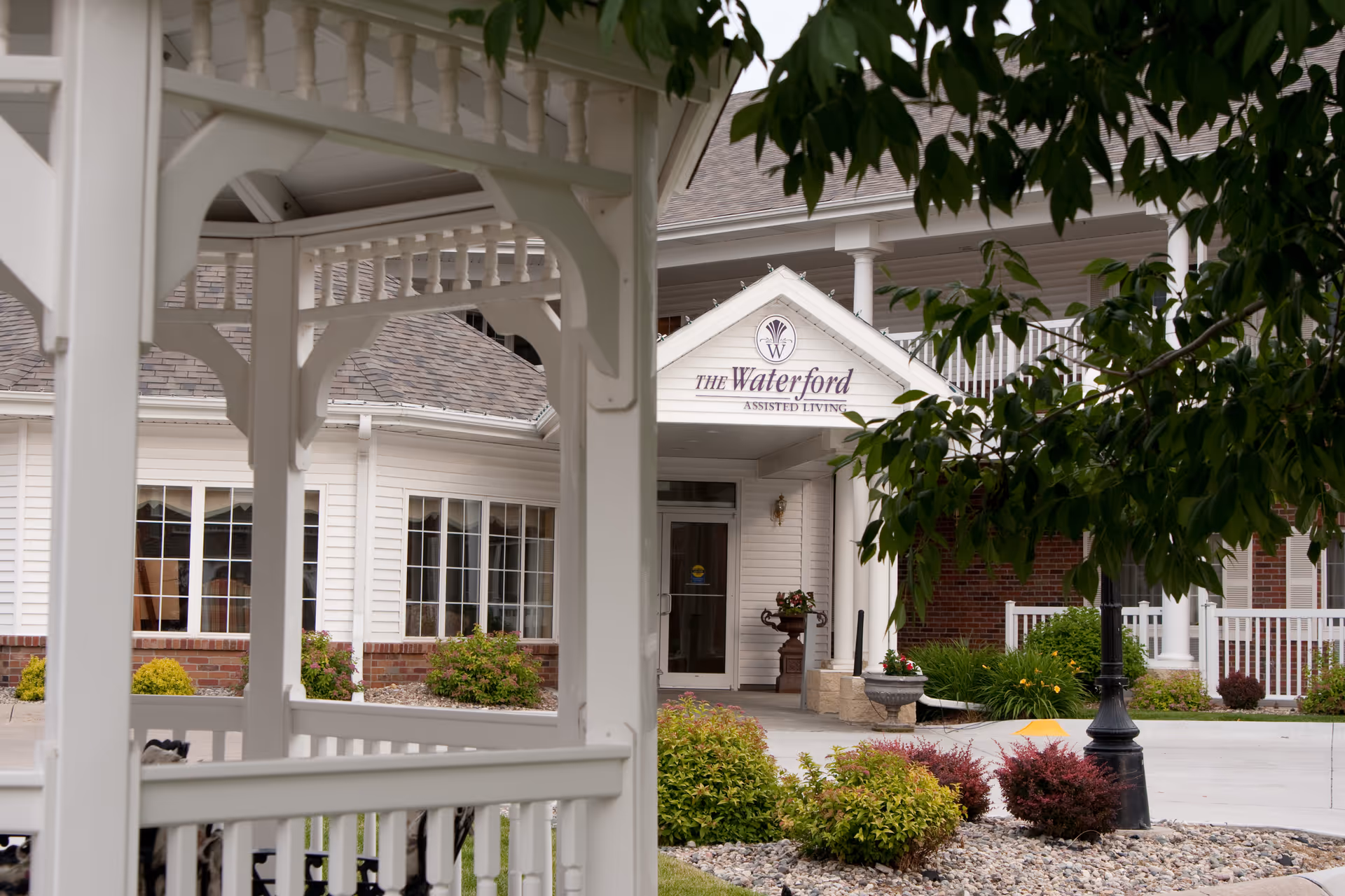 White senior living facility entrance with Waterford sign and landscaped front yard.