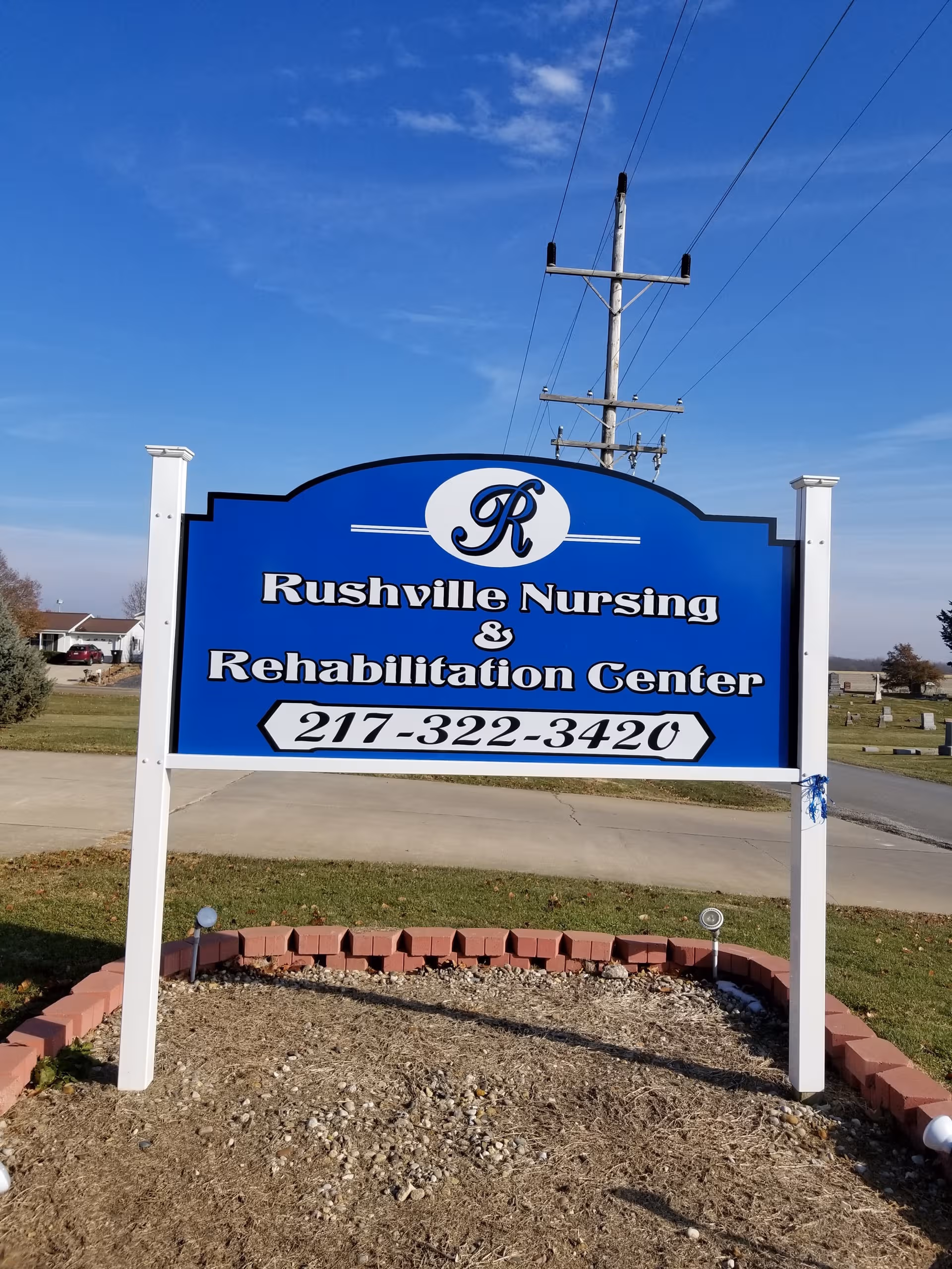 A blue Rushville Nursing & Rehabilitation Center sign sits outdoors.