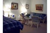 Cozy living area in a senior facility with sofa, chairs, and framed art.