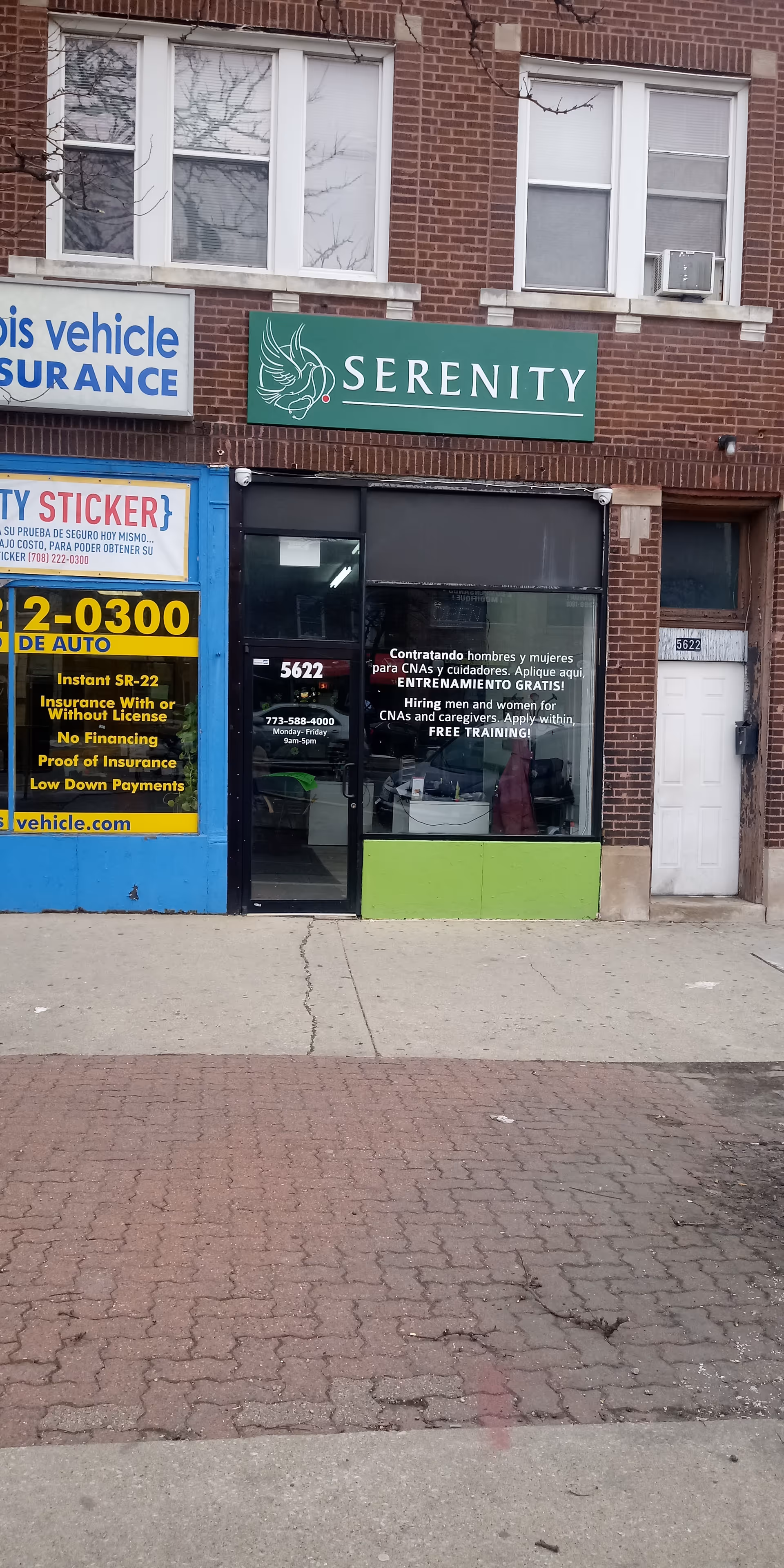 Brick storefront with a green Serenity sign and glass entrance on a city street.