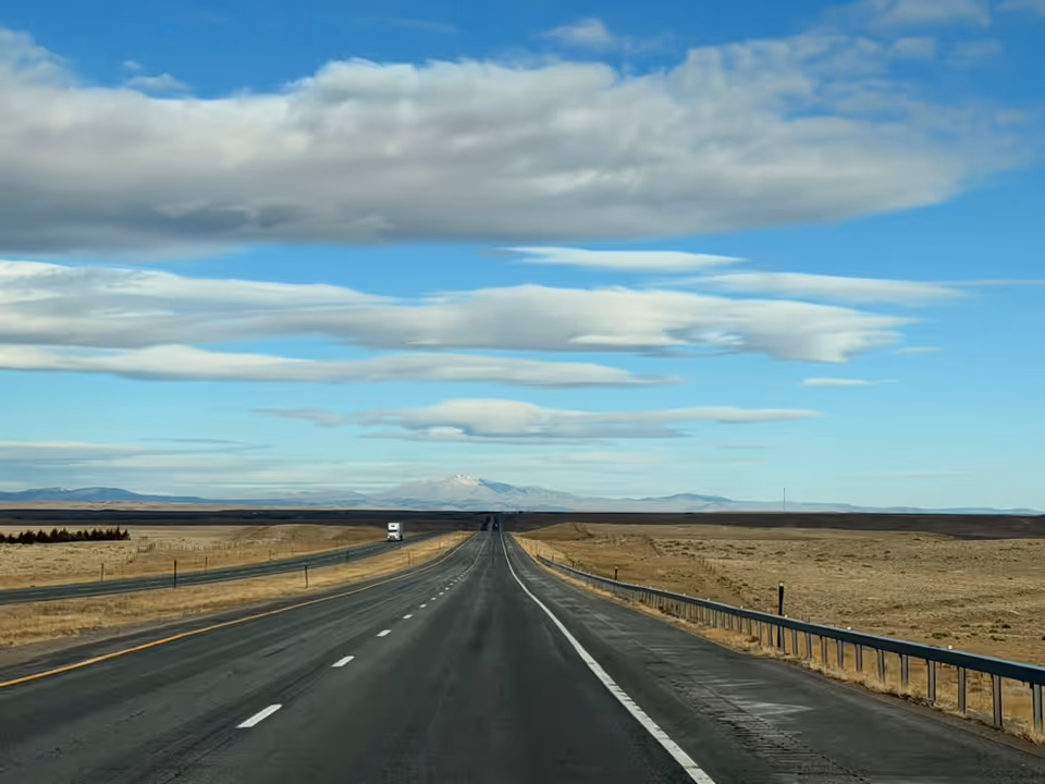 Long straight highway through a desert landscape under blue sky.