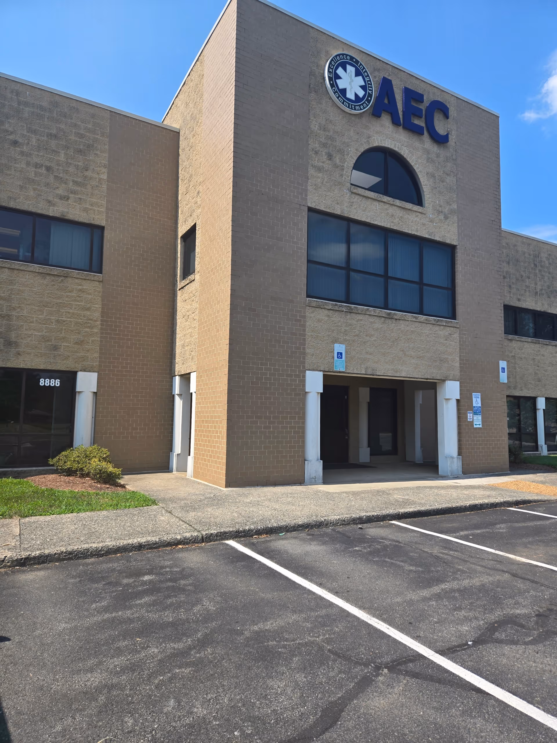 Exterior view of a beige brick healthcare building with AEC sign and entrance.