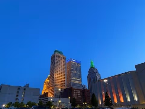 Downtown city skyline at dusk with tall illuminated buildings.