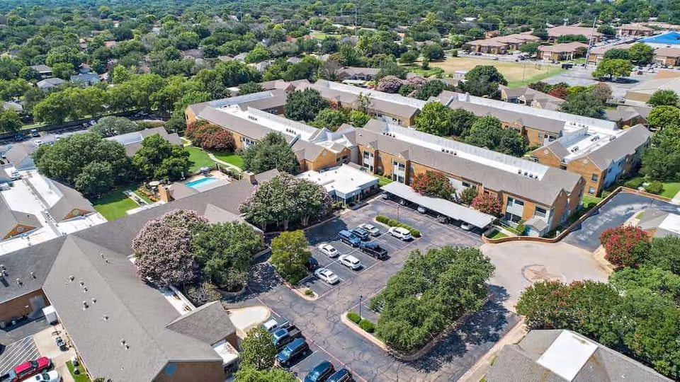 Aerial view of Morada Temple senior living facility surrounded by greenery and parking.