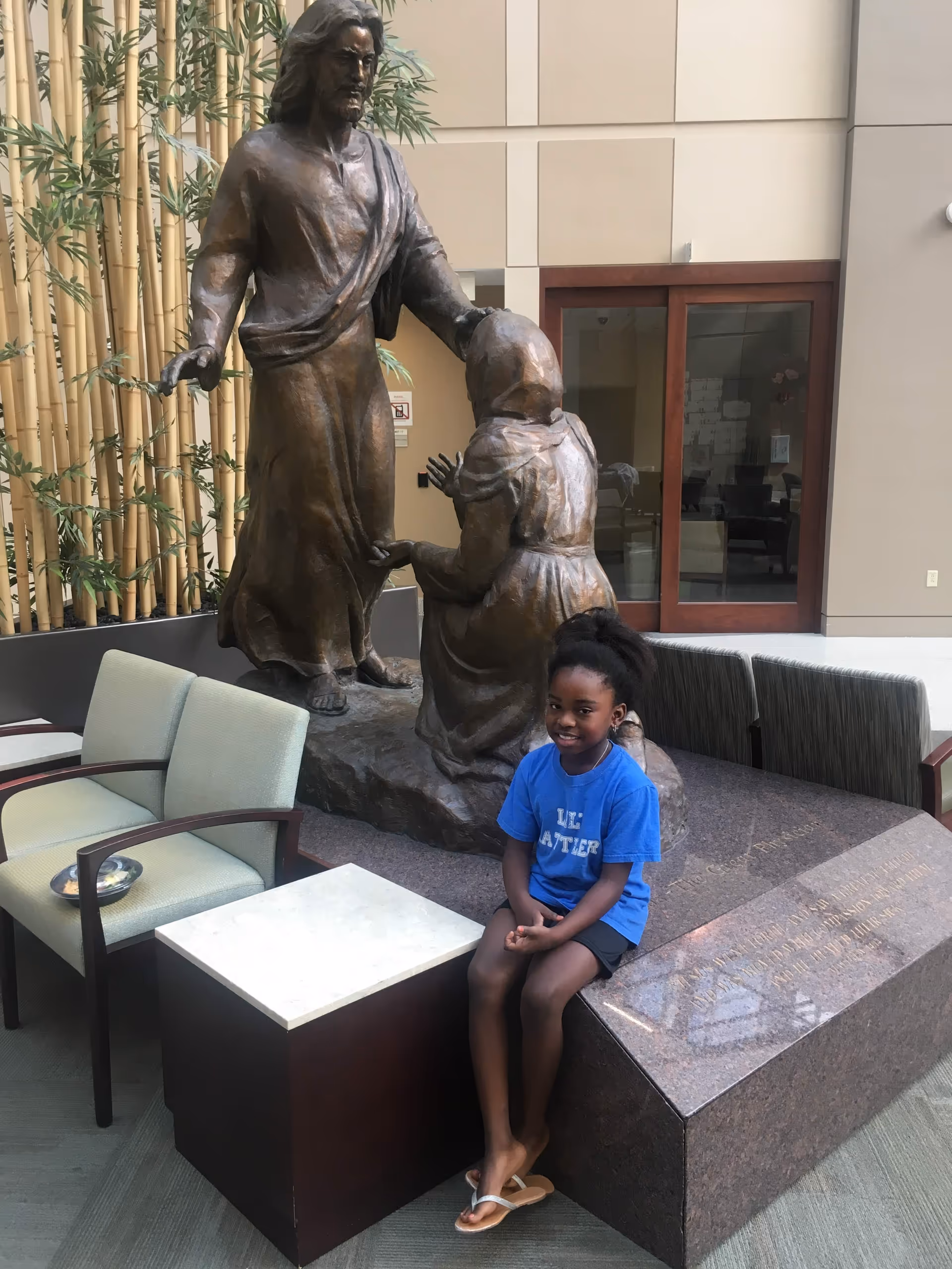 Statue of Jesus with a kneeling child in a modern indoor lounge area