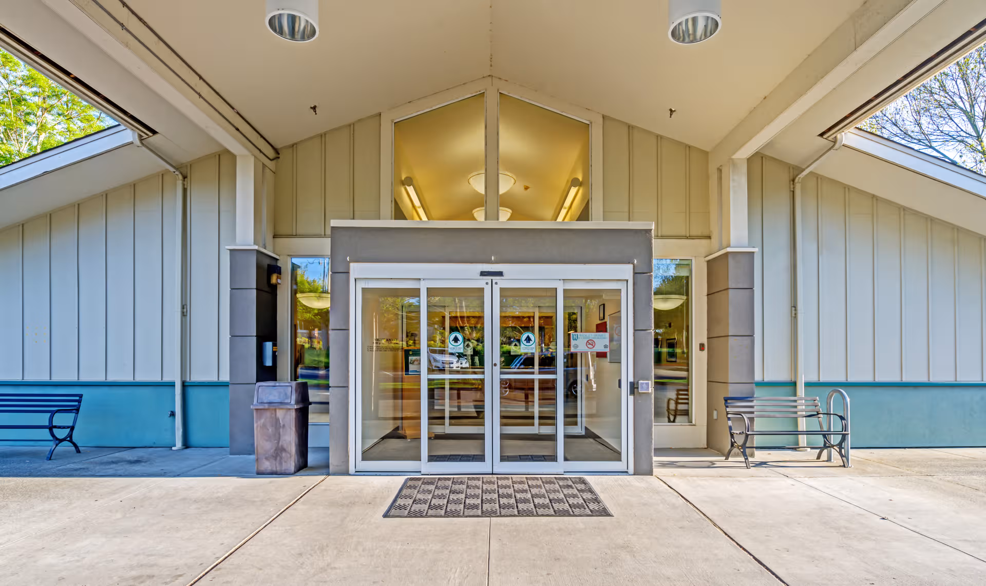 Front entrance of Wesley Des Moines Rehabilitation and Care Center with glass doors and benches.