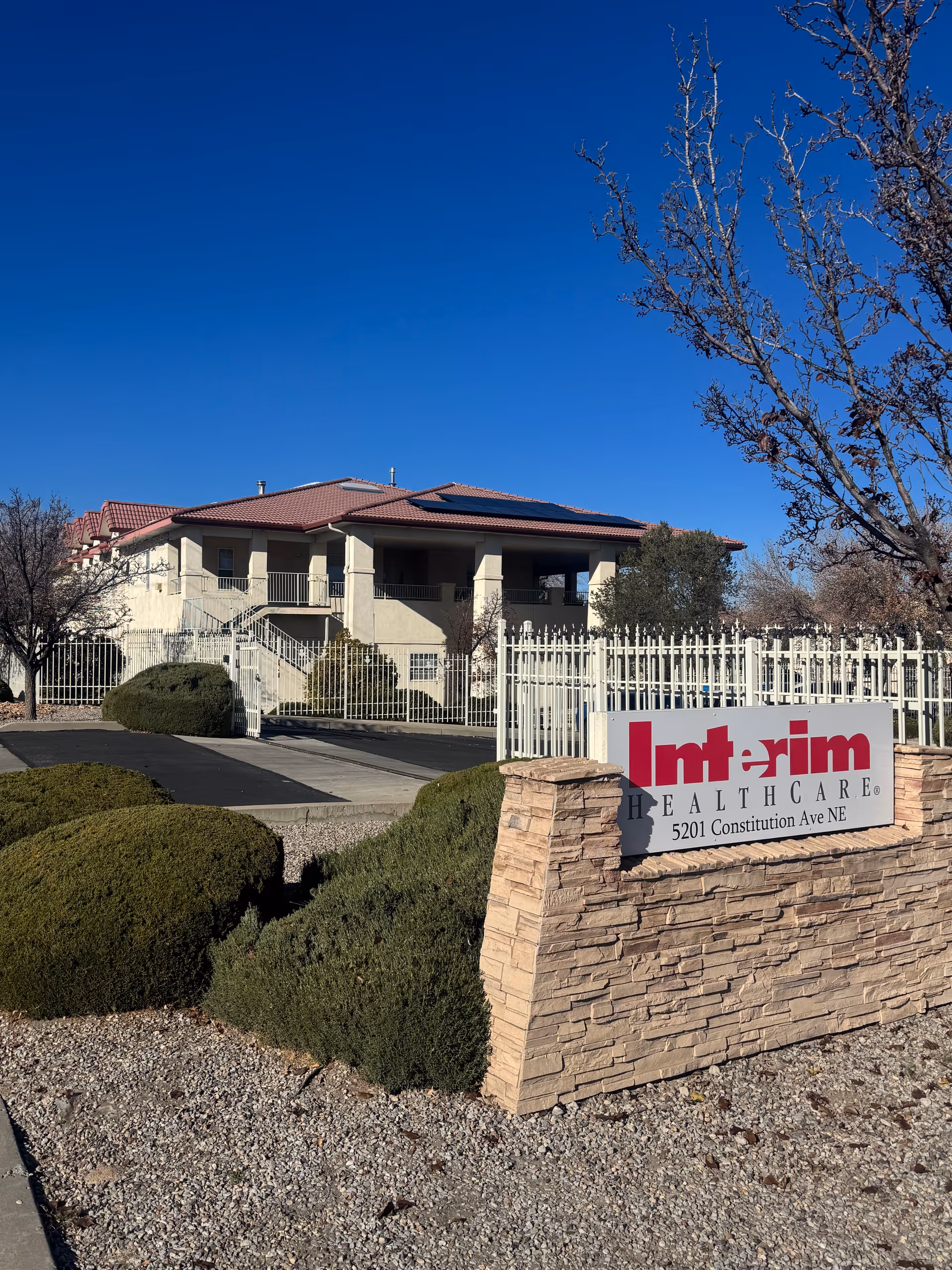 Exterior view of Interim HealthCare of Albuquerque with sign and landscaped entrance.