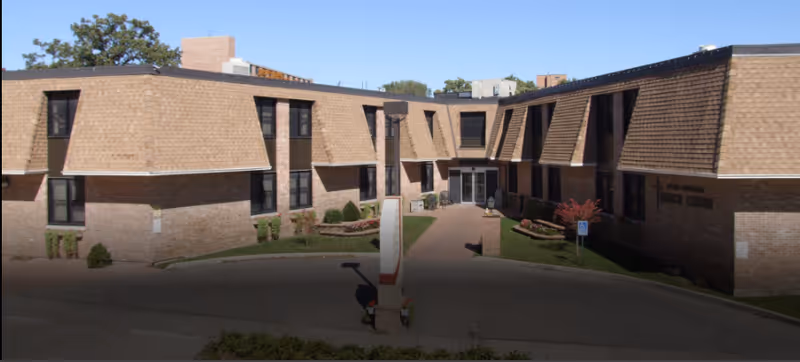 Brick senior living facility with two wings surrounding a central entrance and curved driveway.