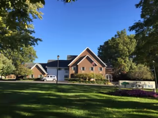 Exterior view of Levy Gardens senior living facility with lawn and trees.