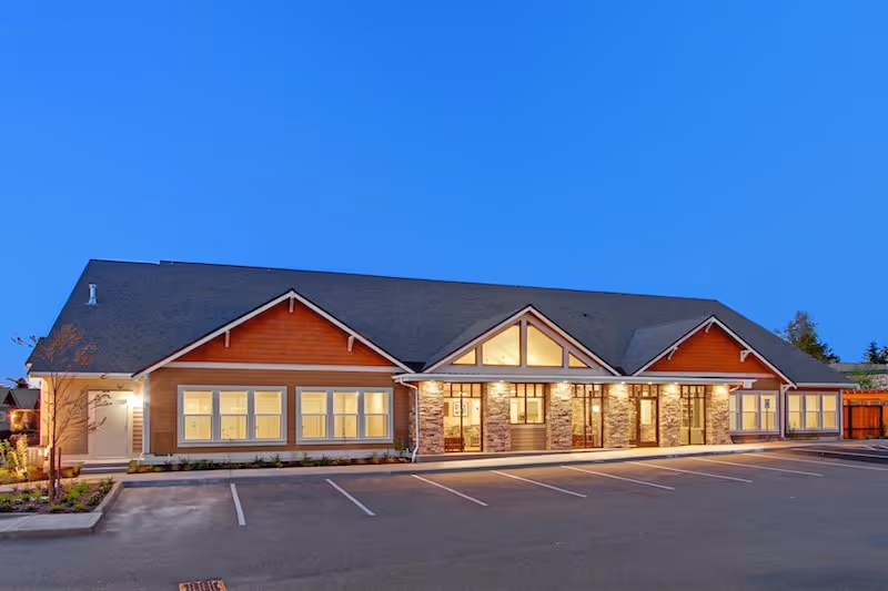 Exterior view of Merrill Gardens at Tacoma, a single-story assisted living facility with parking.