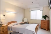 A senior living facility bedroom with a bed, chair, and dresser.