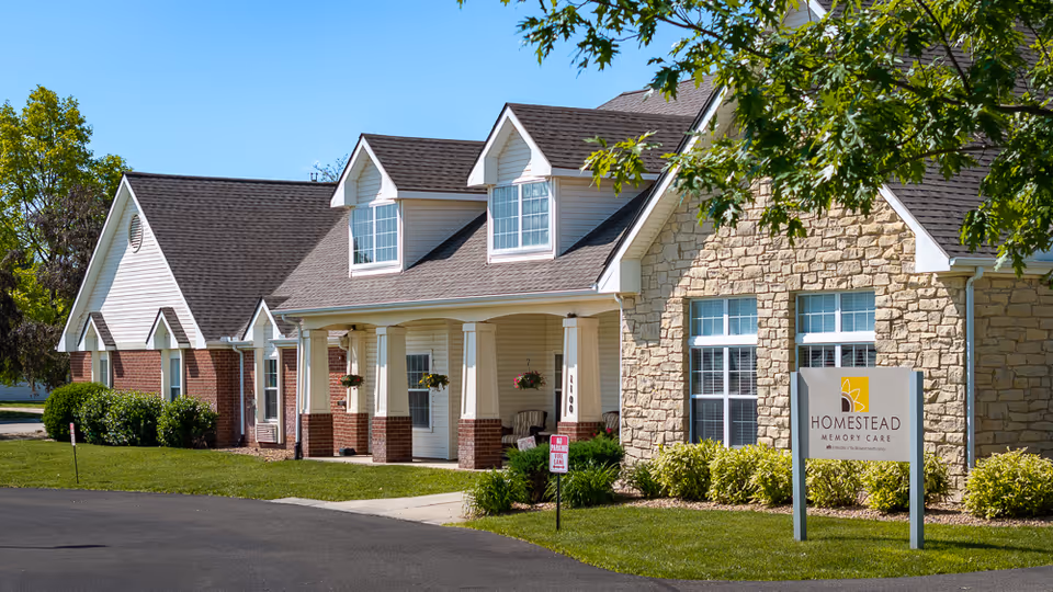 Exterior view of a senior living facility with a stone facade and sign.