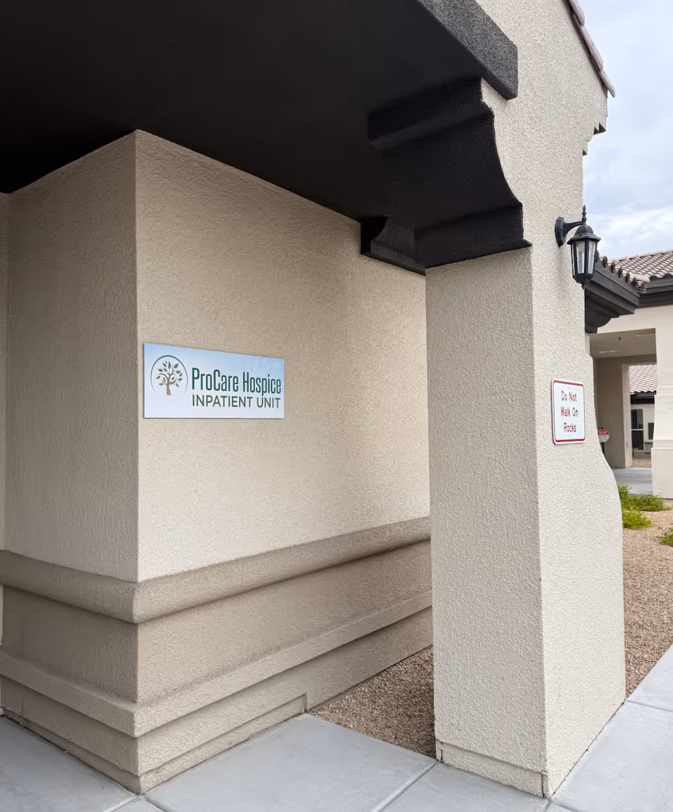 Exterior view of ProCare Hospice Inpatient Unit entrance with sign on beige wall