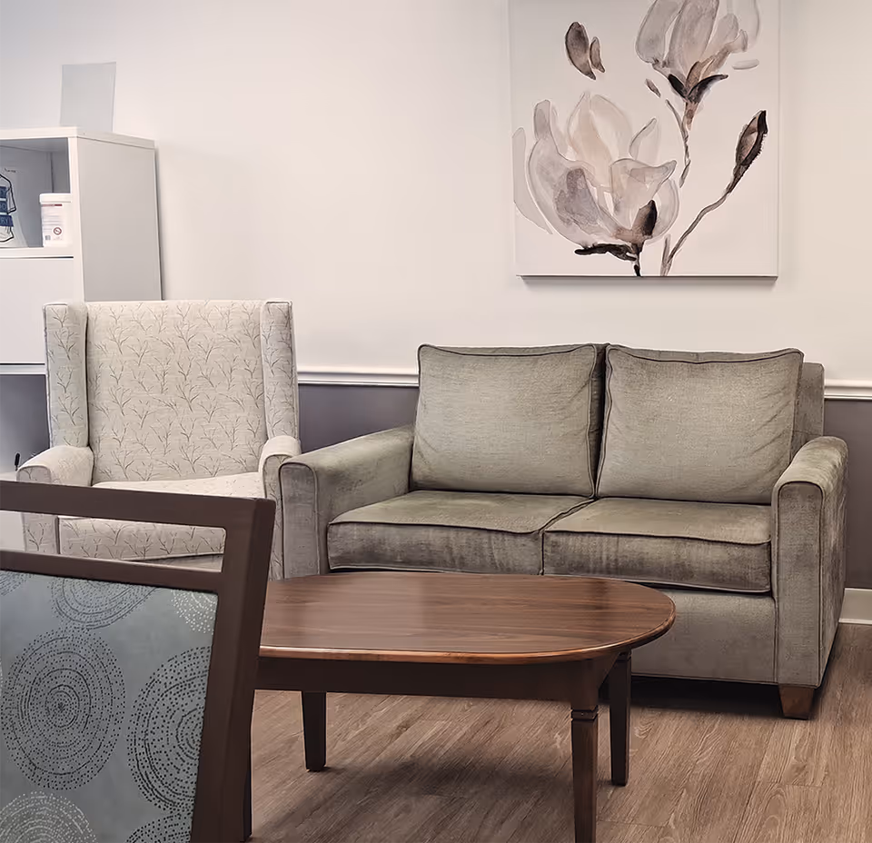 A cozy living room seating area with sofa, armchair, coffee table, and wall art.