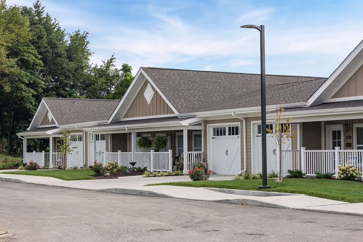 Single-story beige senior living facility with white porches and manicured landscaping.