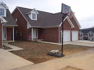 Exterior of Bluegrass Assisted Living building with brick facade, garages, and basketball hoop.