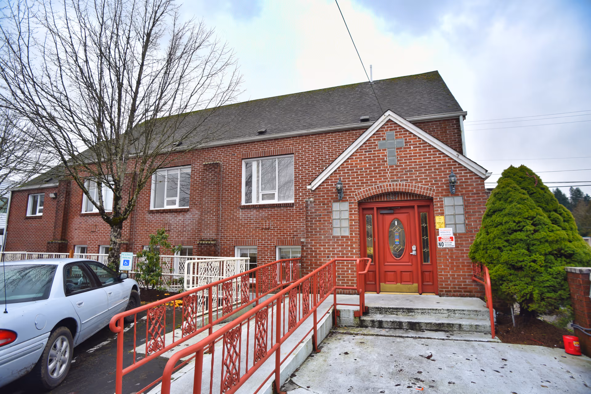 Brick clinic building with a red front door, accessible ramp, and parking.