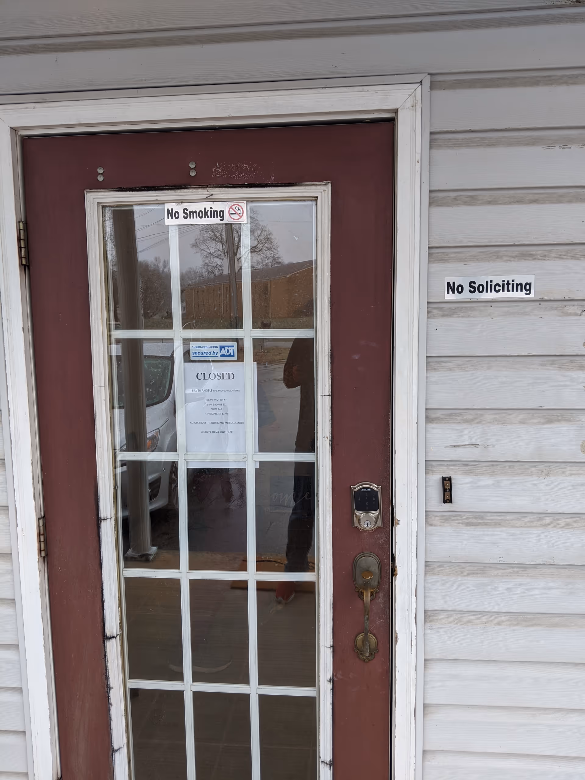 Front entrance door with glass panes and No Smoking and No Soliciting signs.