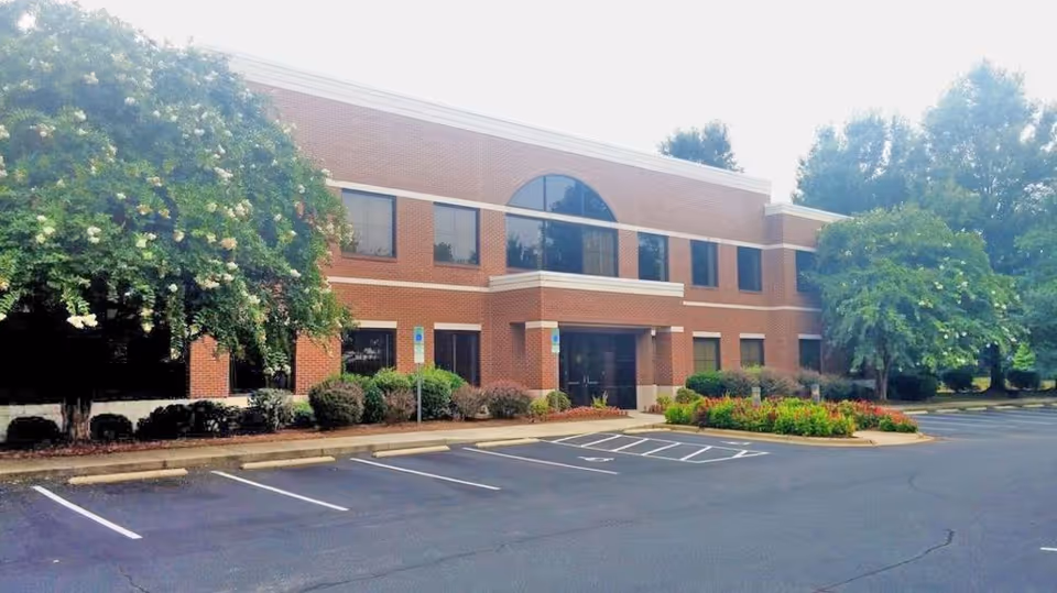 Exterior of A Hand to Help Home Care building with parking and greenery.