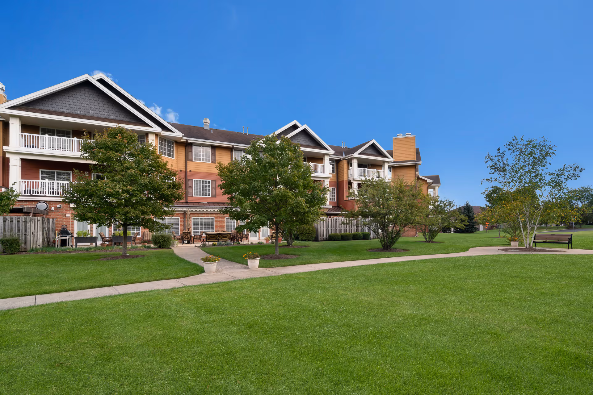 A multi-story senior living building with balconies along a green, well-kept lawn.