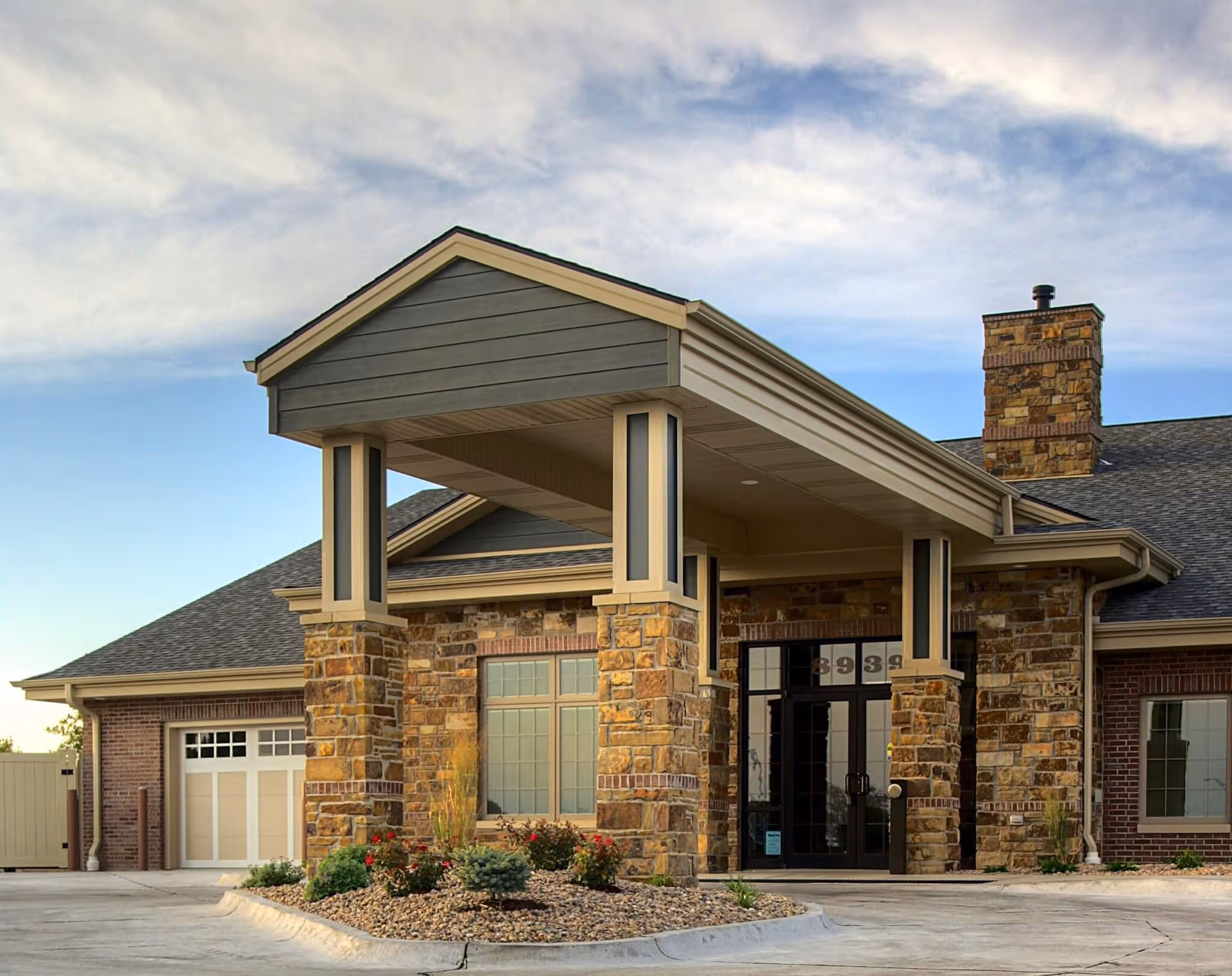 Senior living facility entrance with stone columns and a covered porte-cochere.