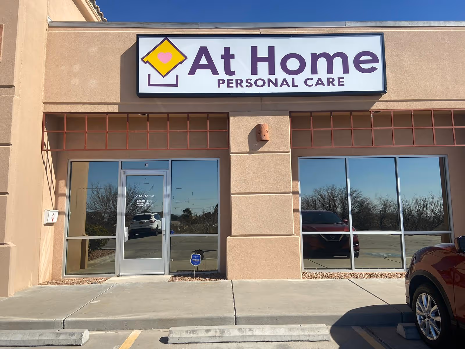 Exterior view of At Home Personal Care storefront with glass doors and large sign.