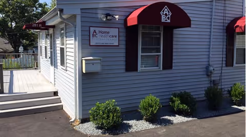 Blue siding exterior of ABC Home Healthcare building with red awnings.