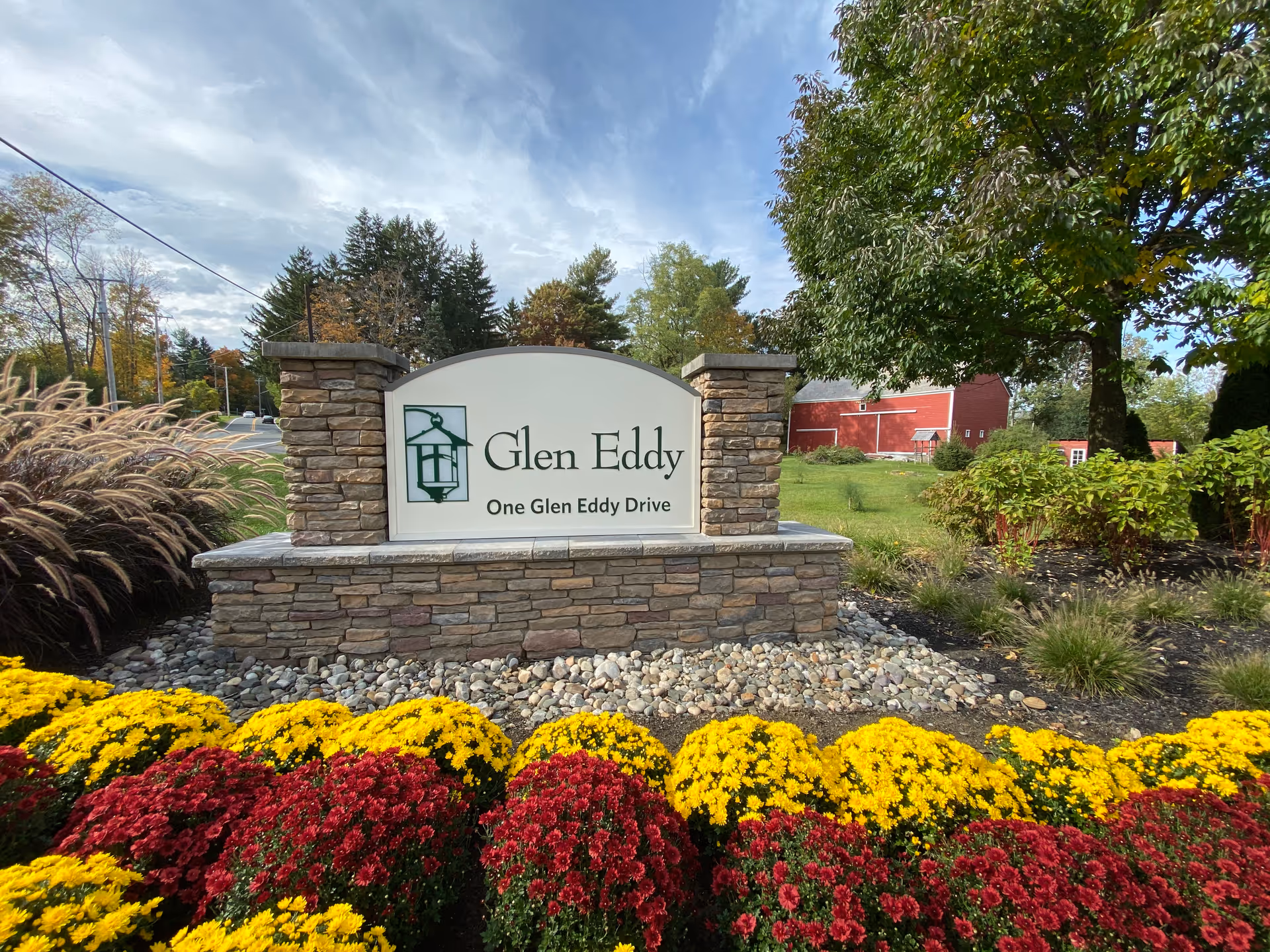 Stone entrance sign for Glen Eddy with colorful flower beds and landscaping