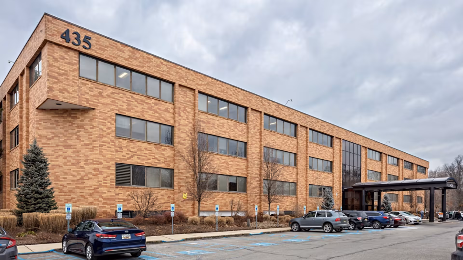 Brick exterior of a senior living facility with parking and a covered entrance.