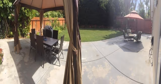 Outdoor patio at Paradise Home & Garden with tables, chairs, umbrellas, and a grassy yard.