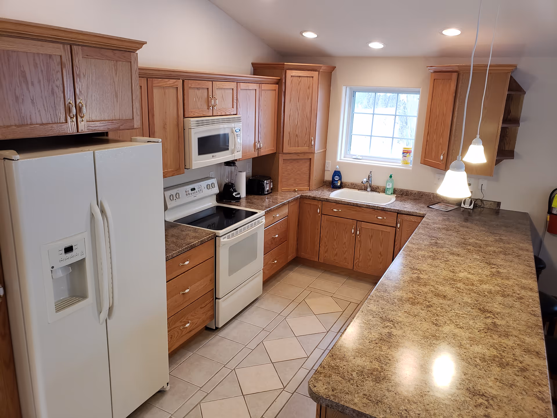 Wooden kitchen with cabinets, white appliances, sink, and an island.
