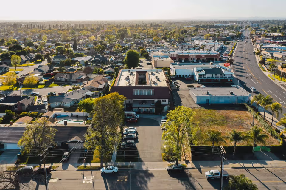 Aerial view of a suburban commercial area with buildings, streets, and trees.